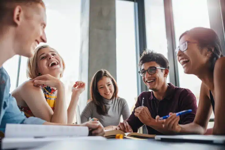 Group of diverse international students laughing and studying together, learning Czech for foreigners at SOLARIS Language School.