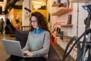 A woman researching individual language course fees online on her laptop in a cozy workspace.